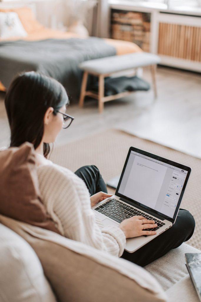 woman typing on keyboard of laptop at home